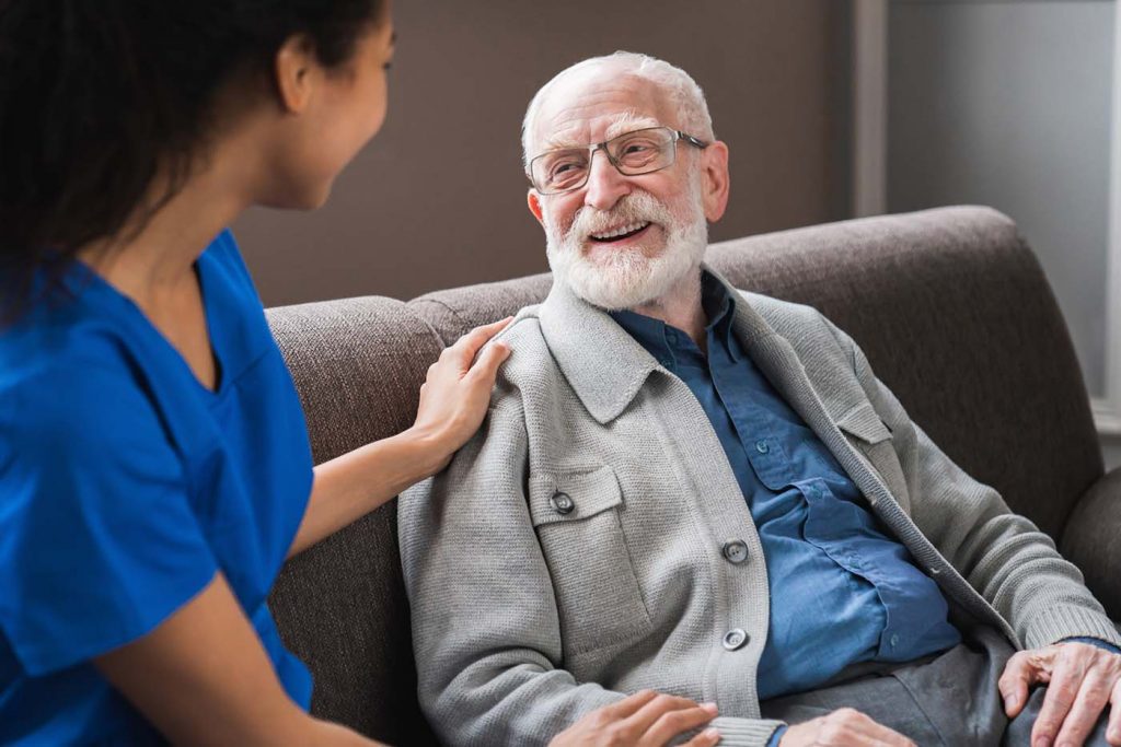 Picture of smiling hospice nurse assisting senior elderly man
