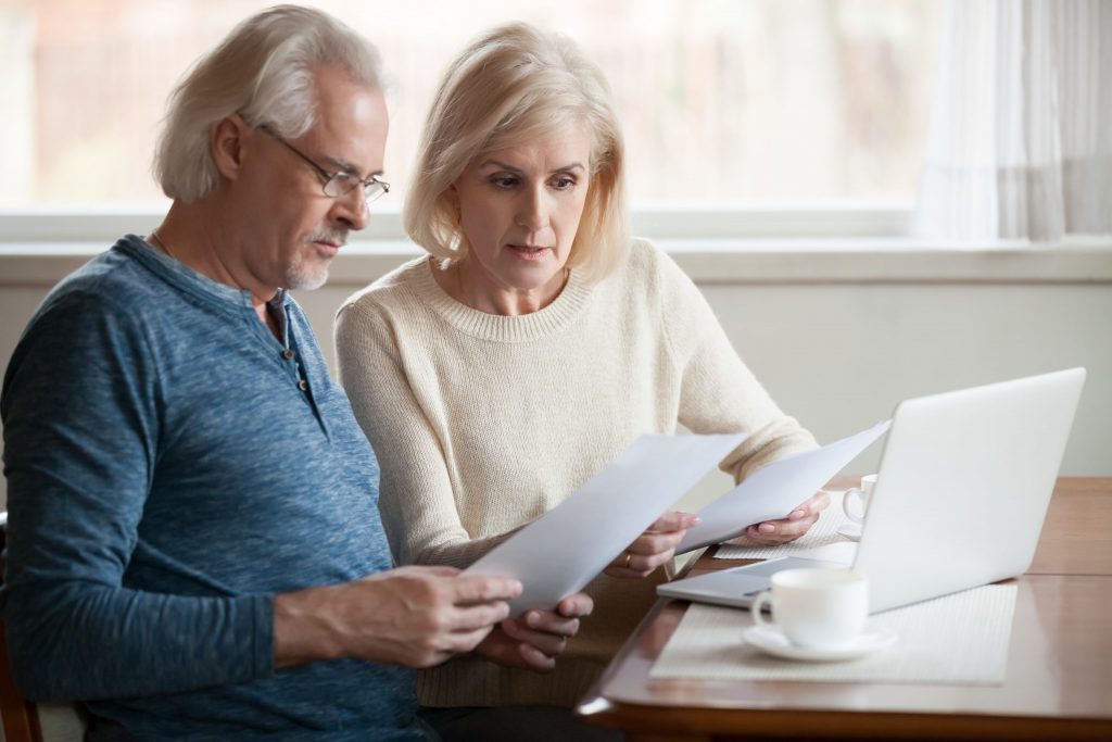Serious worried senior couple reading documents